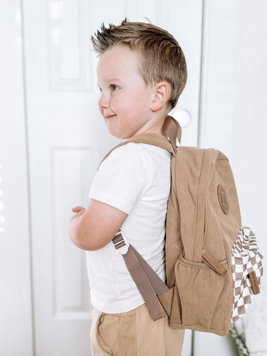 boy stands looking proud while wearing a backpack by Rad Toddler