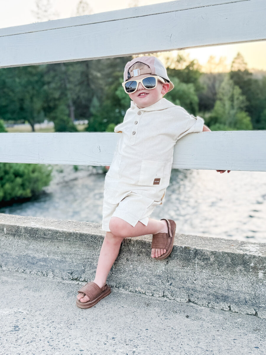boy standing on a Pier wearing a comfortable beige linen outfit with a leather patch by Rad toddler